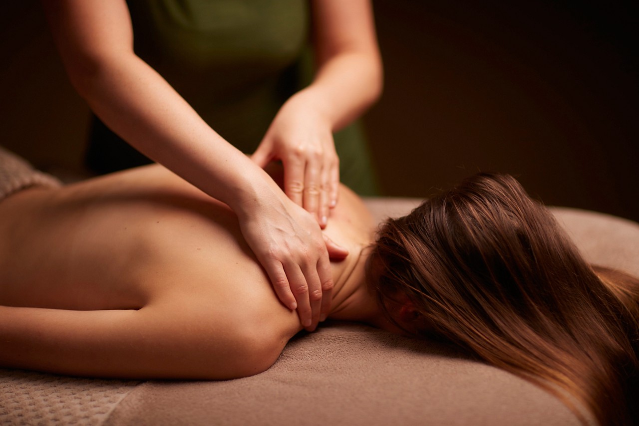 Spa therapist giving a woman a relaxing back massage body treatment.